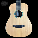 A natural wood acoustic guitar shown from the front against a solid black background, featuring a light tan wood body, black neck and headstock, and blue decorative rings around the soundhole.