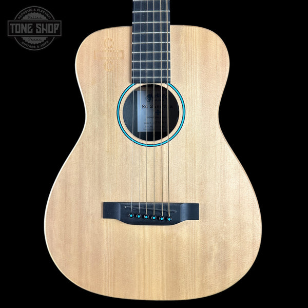 A natural wood acoustic guitar shown from the front against a solid black background, featuring a light tan wood body, black neck and headstock, and blue decorative rings around the soundhole.