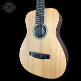A natural wood acoustic guitar shown from a three-quarters angle against a solid black background, with a Tone Shop watermark in the top-left corner.
