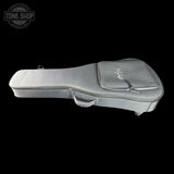 A light gray padded guitar or ukulele case shown from the side against a solid black background, with a small Tone Shop watermark in the upper left corner.