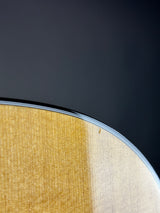 Extreme close-up of a curved wooden surface with a light natural wood finish against a dark charcoal background.