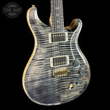 Electric guitar with a unique wood finish on a black background, featuring the Tone Shop logo.
