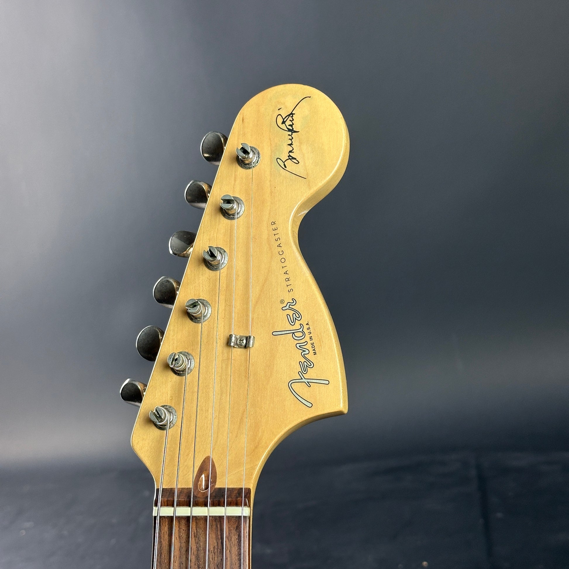 Close-up of a Fender Stratocaster guitar headstock on a dark background