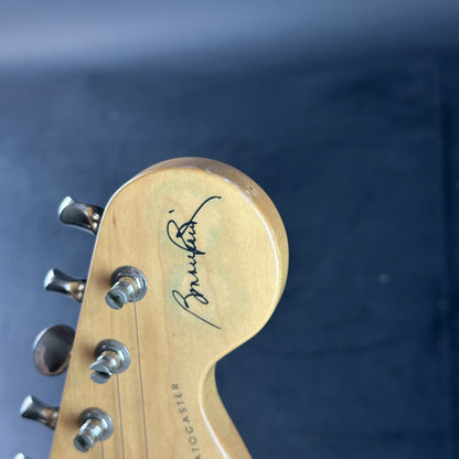 Close-up of a guitar headstock with a brand logo on a dark background