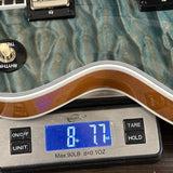Close-up of an electric guitar body resting on a digital scale displaying 8.77 lbs.