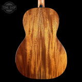 Back view of a wooden acoustic guitar with 'Tone Shop' logo.