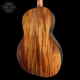 Close-up of a wooden acoustic guitar on a black background with 'Tone Shop' logo.