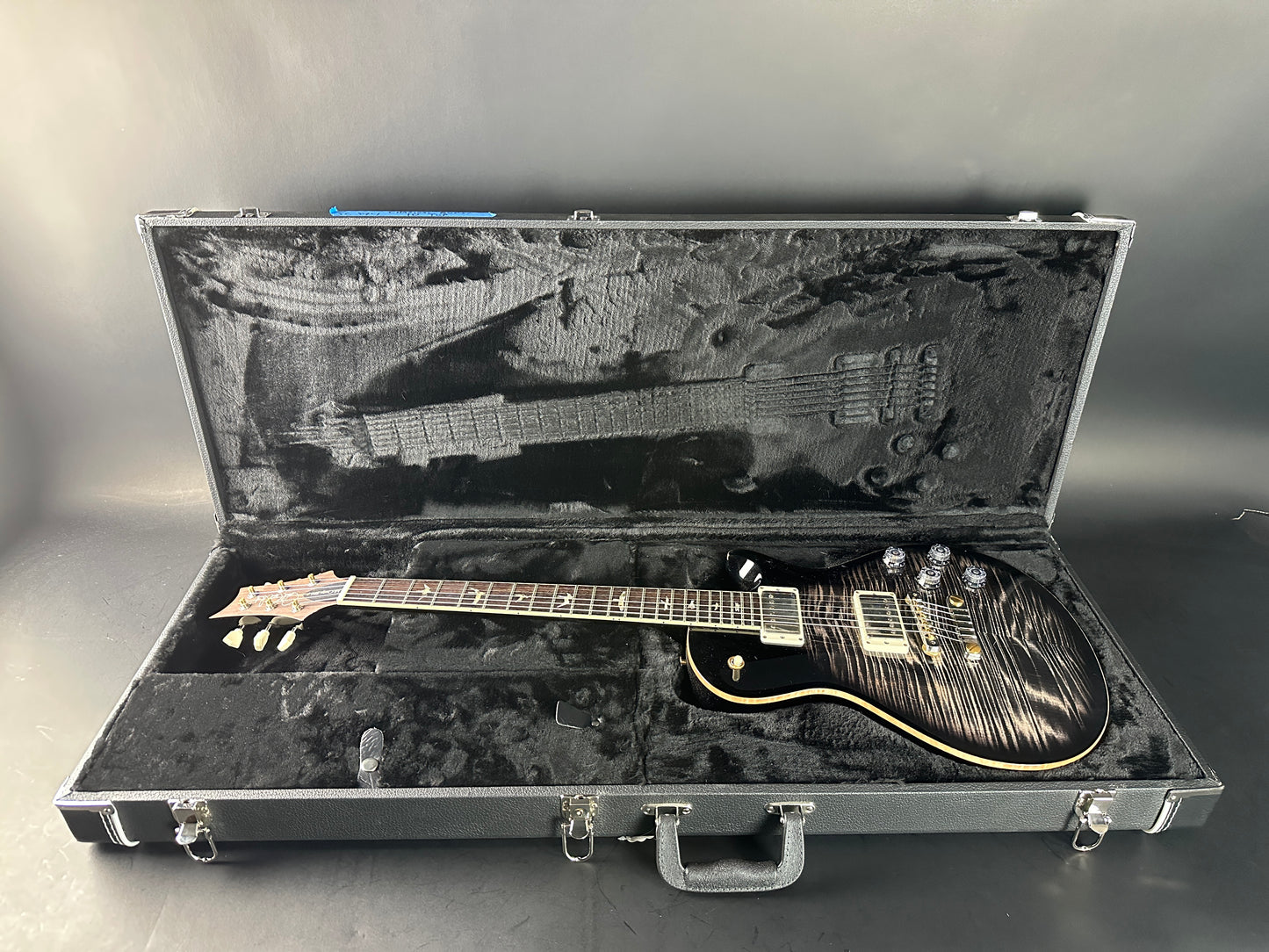 Electric guitar in an open hard-shell case on a gray background