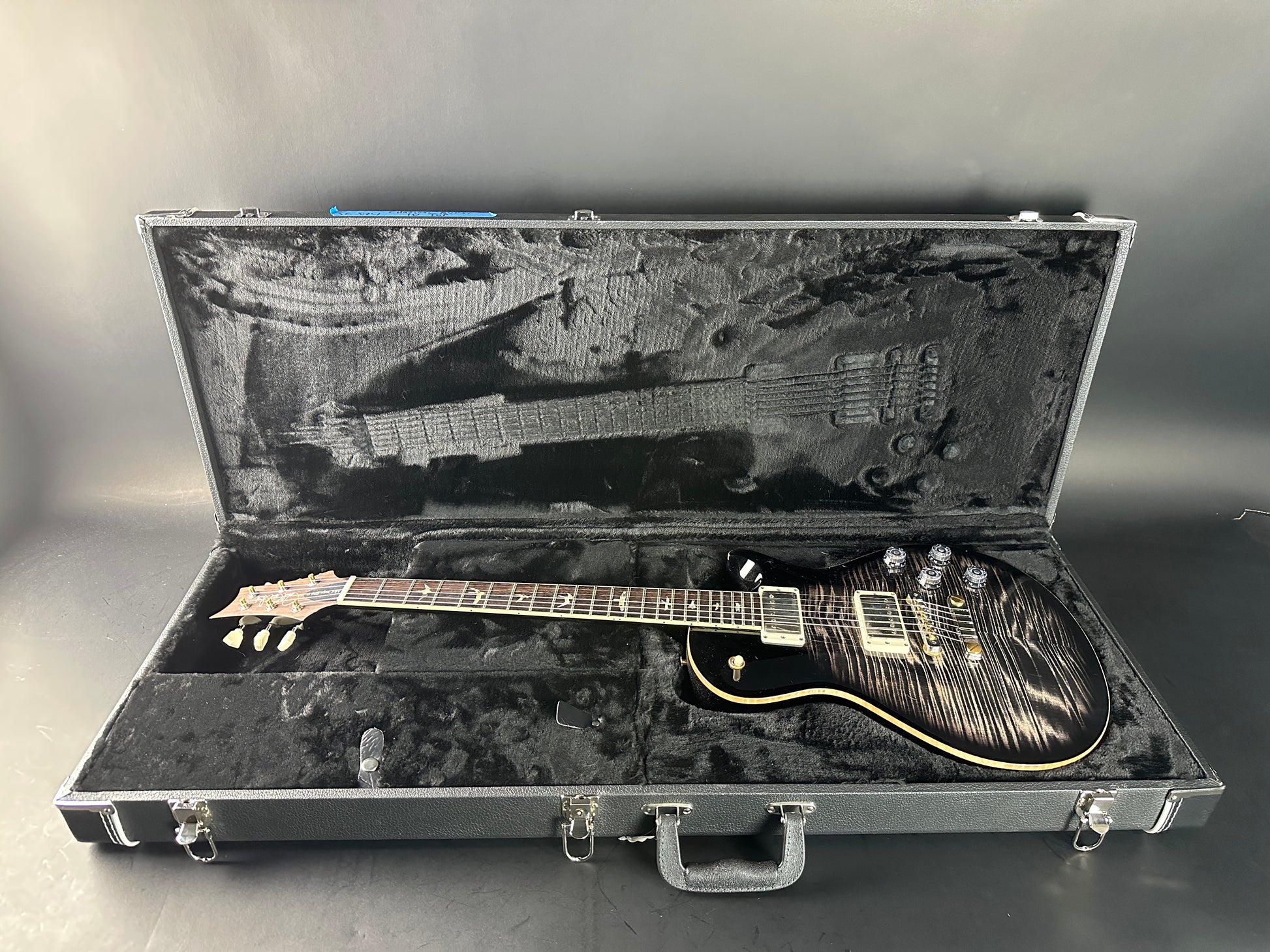 Electric guitar in an open hard-shell case on a gray background