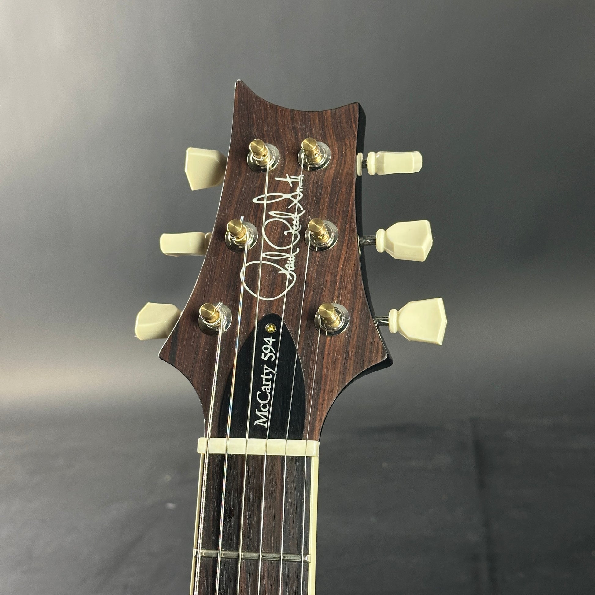 Guitar headstock with brand name on a dark background
