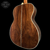 Back view of a wooden acoustic guitar with 'Tone Shop' logo.