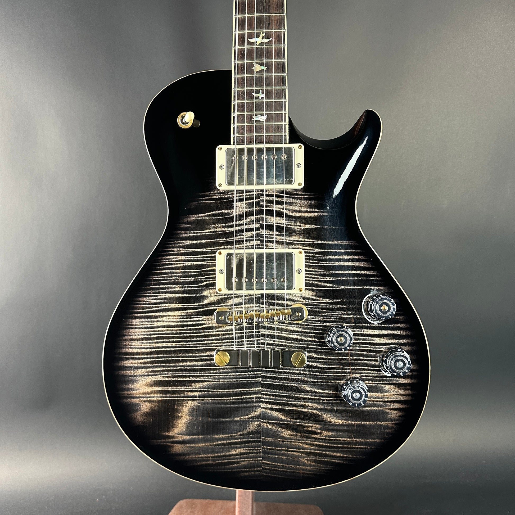 Black electric guitar with a unique pattern on the body against a gray background