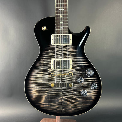Black electric guitar with a unique pattern on the body against a gray background