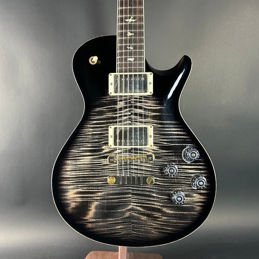 Black electric guitar with a unique pattern on the body against a gray background