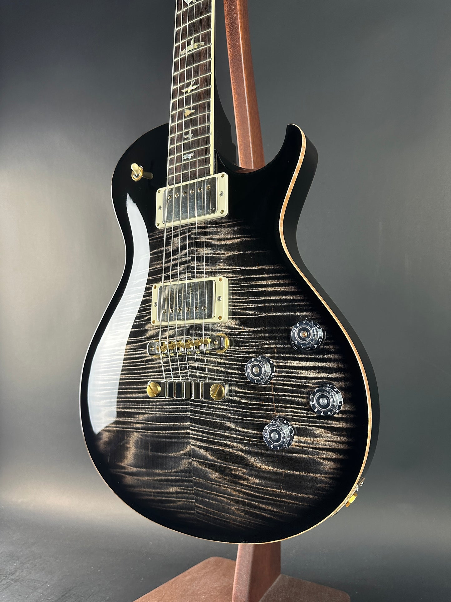 Black electric guitar with a unique wood grain pattern on a gray background