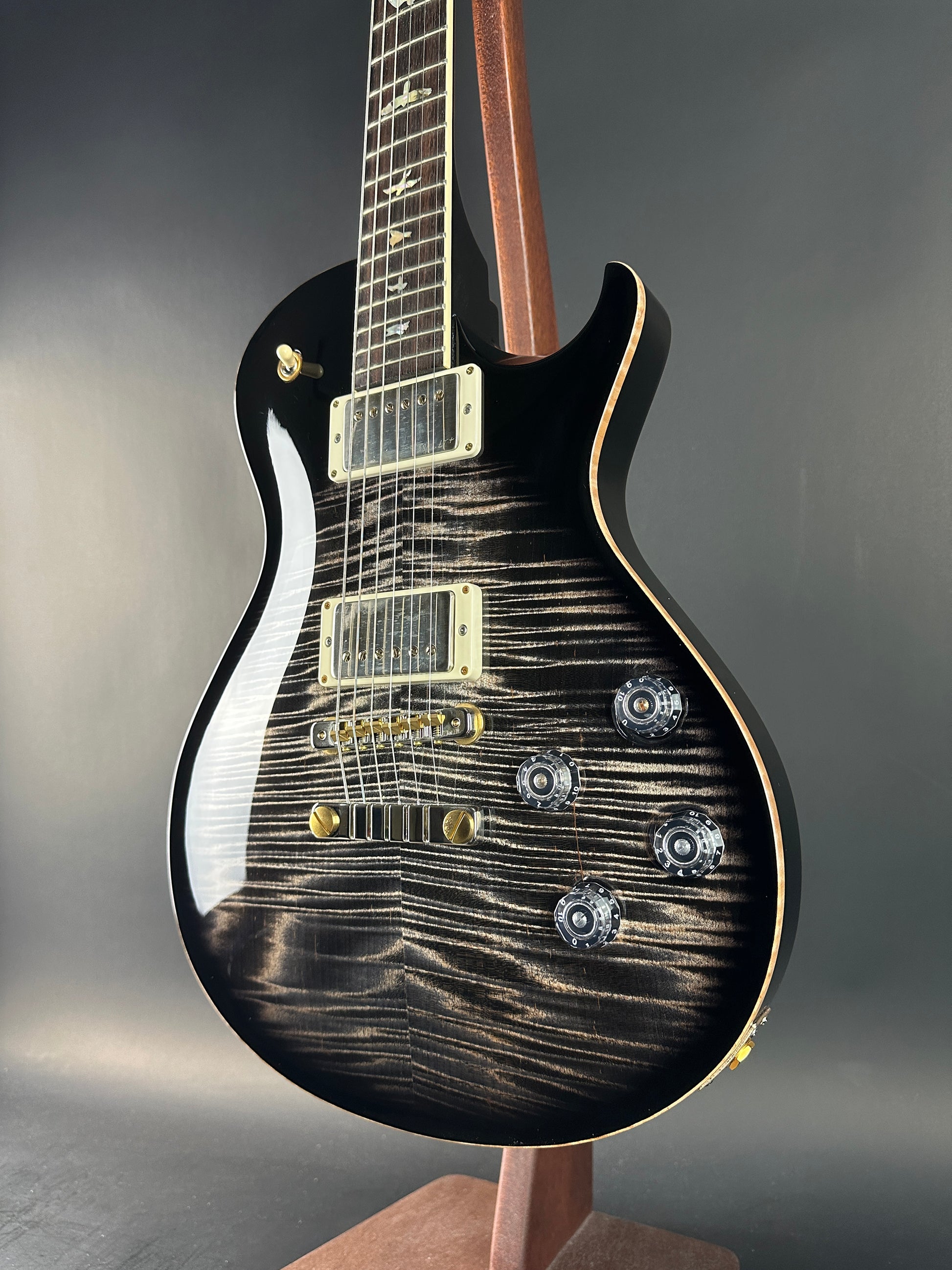 Black electric guitar with a unique wood grain pattern on a gray background