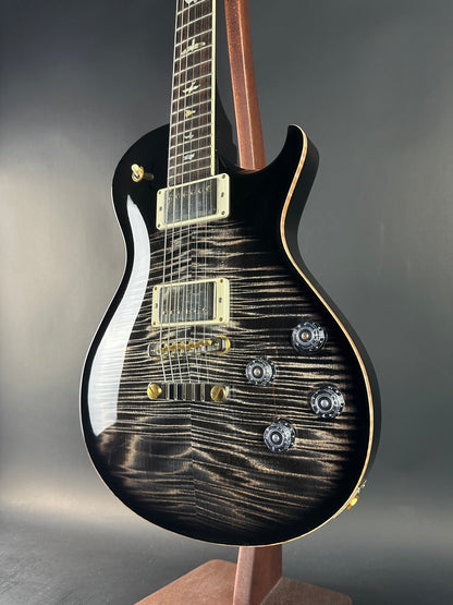 Black electric guitar with a unique wood grain pattern on a gray background