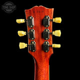 Close-up of a guitar headstock with tuning pegs on a black background, featuring the Tone Shop logo.