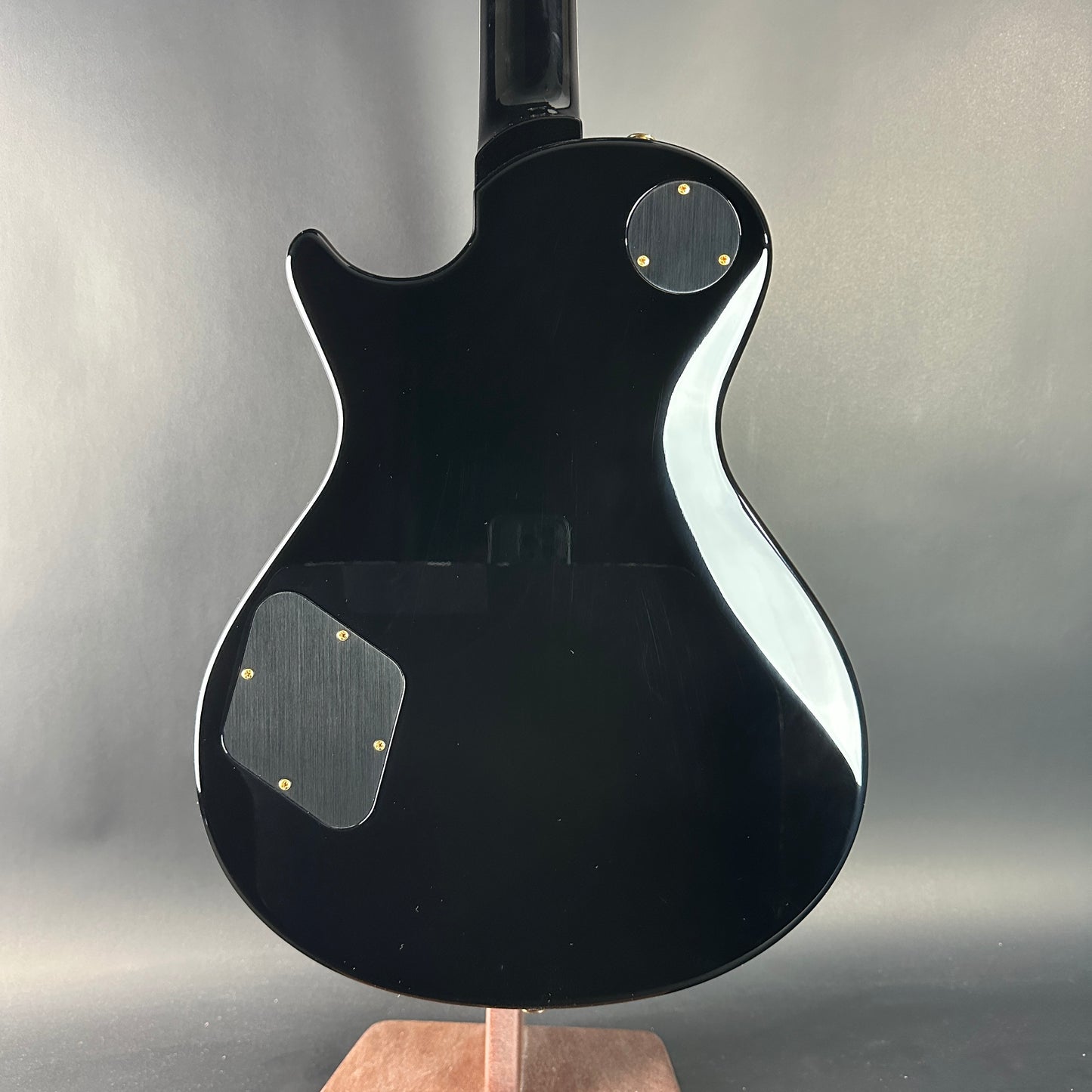 Black electric guitar on a stand against a gray background