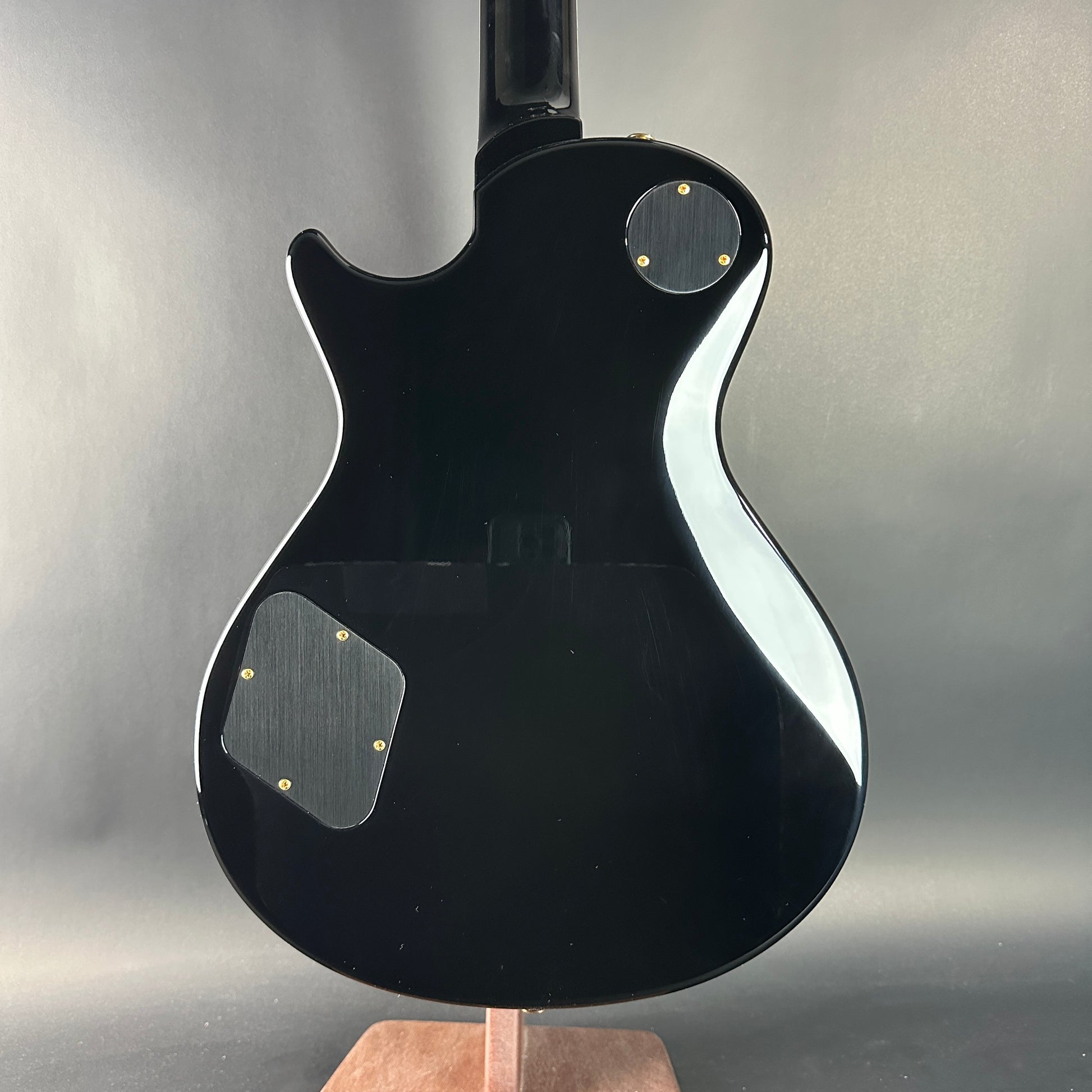 Black electric guitar on a stand against a gray background
