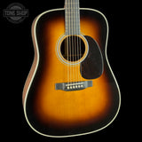 A classic acoustic guitar with a sunburst finish, featuring a warm amber center fading to black around the edges, shown against a solid black background.