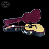 Acoustic guitar in a case with 'Tone Shop' branding on a black background