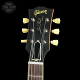 Close-up of a Gibson Les Paul ES-311 electric guitar headstock, featuring a black finish, gold Gibson logo, Les Paul script, and cream-colored tuning pegs against a black background.