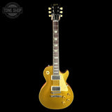 A gold-finish electric guitar with a dark fretboard and cream pickguard, shown against a solid black background. A Tone Shop watermark is visible in the top-left corner.