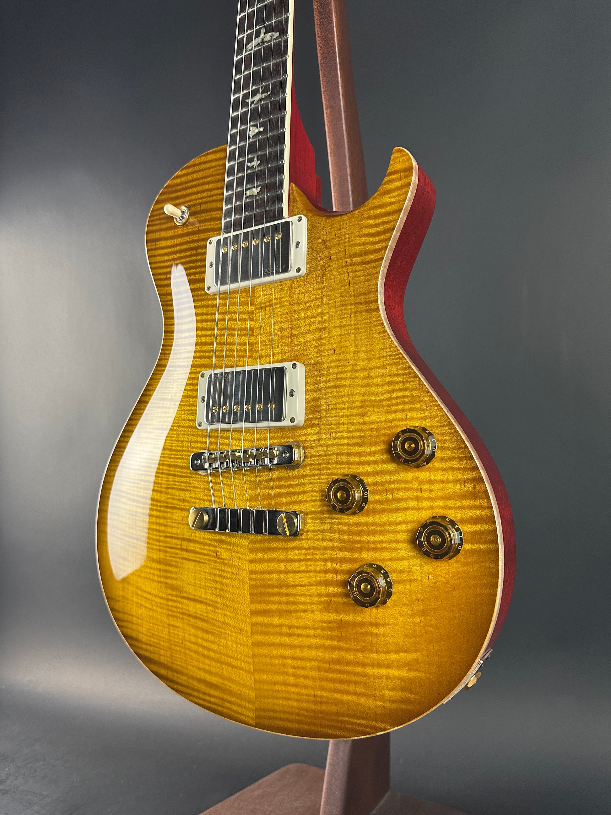 Close-up of a guitar with a yellow finish on a gray background