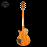 A Gibson electric guitar shown from the back, featuring a glossy natural wood finish and a circular soundhole badge, set against a solid black background with a Tone Shop watermark in the top left corner.