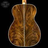 Close-up of a wooden acoustic guitar back with 'Tone Shop' logo.