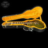 An electric guitar with a metallic olive green finish resting inside an open black hard case with a bright yellow-orange velvet interior, shown against a solid black background.