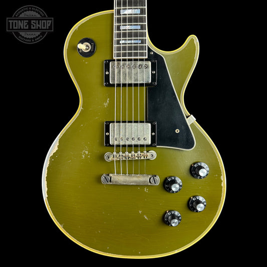 A vintage-style electric guitar with a distressed olive green finish, black pickguard, and chrome hardware, shown against a solid black background with a Tone Shop watermark in the top left corner.