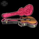 Acoustic guitar in a black case with pink interior on a black background, featuring 'Tone Shop' logo.