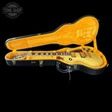 A gold-finish electric guitar inside an open black hard case with bright orange velvet lining, shown against a black background. A Tone Shop watermark is visible in the top-left corner.