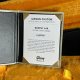 A Gibson Custom Certificate of Authenticity insert for a Murphy Lab Ultra Light Aging instrument, displayed inside an open presentation folder on a textured gold fabric background.
