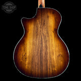 Back view of a wooden acoustic guitar with a dark brown finish on a black background, featuring the Tone Shop logo.