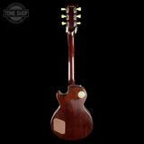 A Gibson electric guitar shown from the back, featuring a glossy dark reddish-brown wood finish, gold tuning pegs, and a gold circular badge on the backplate, set against a solid black background.