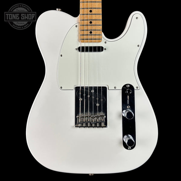 White electric guitar with a black pickguard on a black background, featuring the Tone Shop logo.