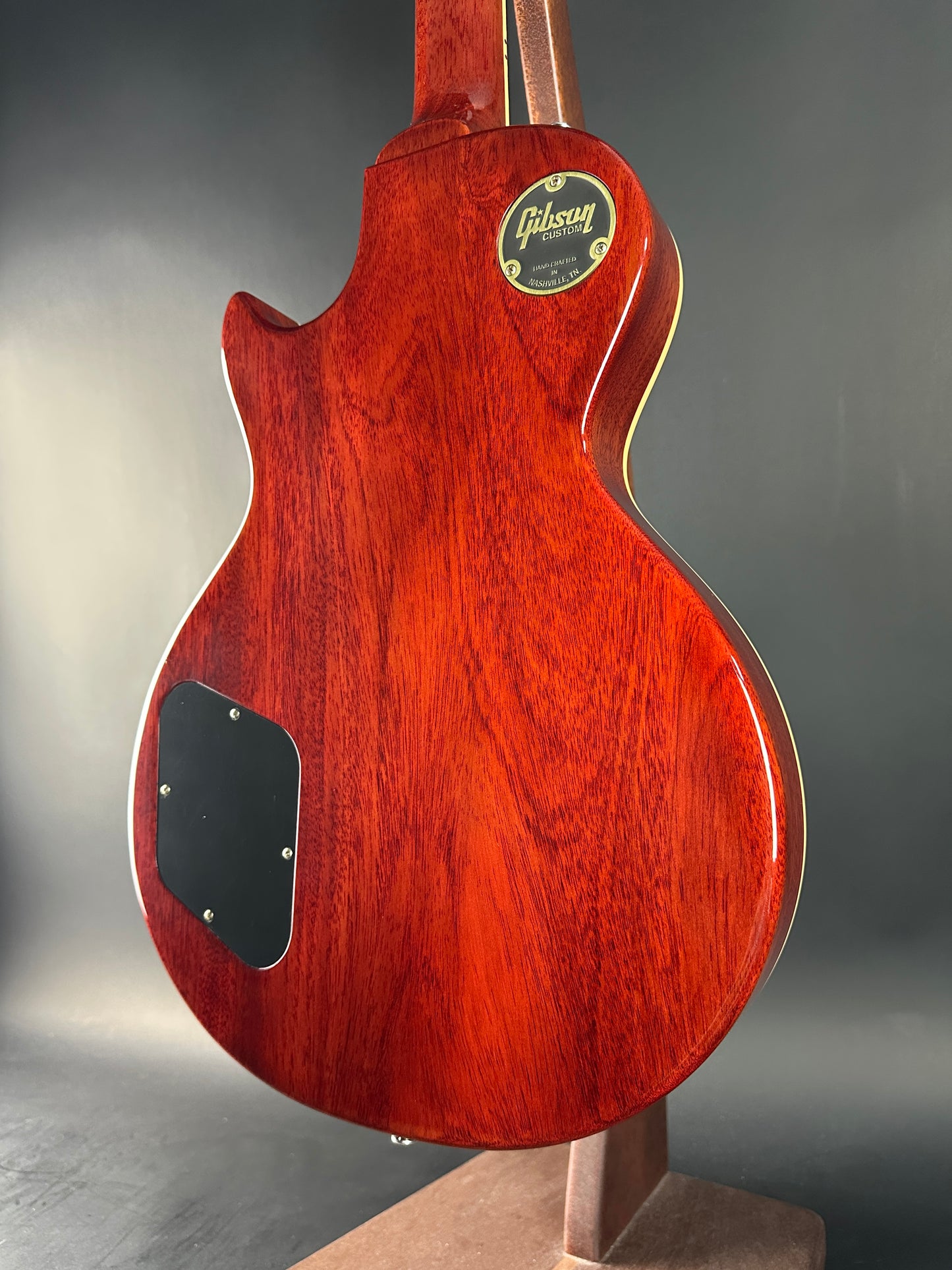 Close-up of a red electric guitar body with a Gibson logo on a gray background