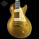 A gold-finish electric guitar with cream pickguards and gold hardware, shown against a solid black background. A Tone Shop watermark is visible in the top-left corner.