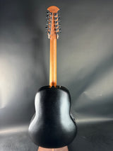 Close-up of a black six-string guitar headstock on a gray background