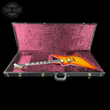 An electric guitar with a sunburst finish resting inside an open hard case lined with textured magenta velvet. The case is shown open against a solid black background, with a Tone Shop watermark in the upper left corner.
