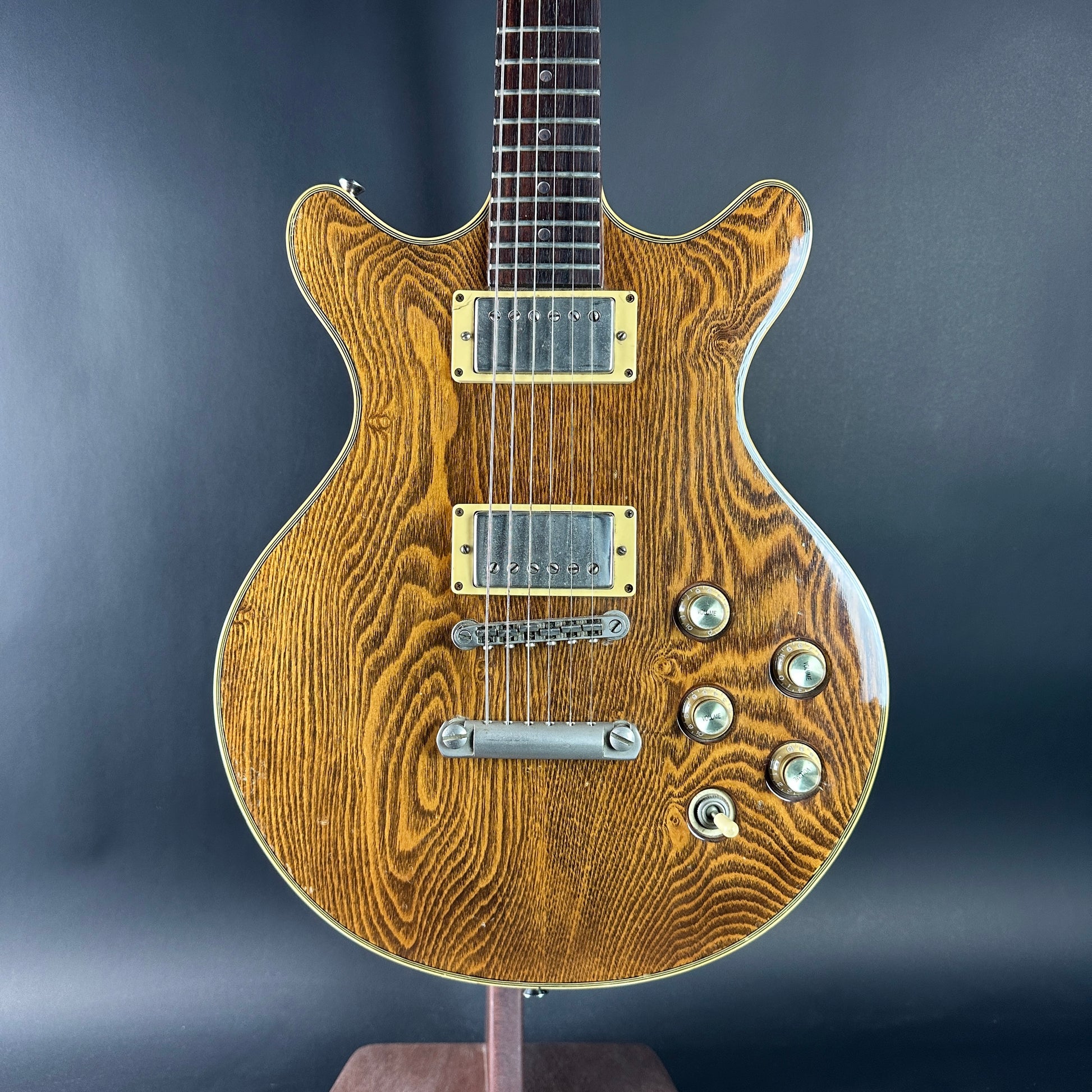 Wooden electric guitar with a wavy grain pattern on a dark background
