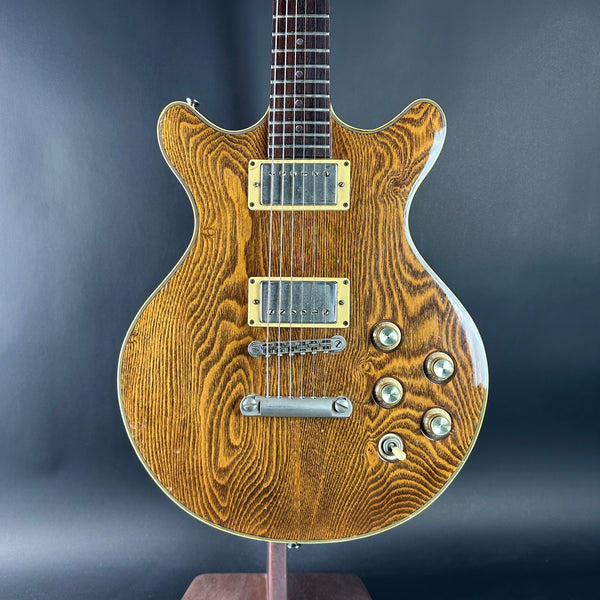 Wooden electric guitar with a wavy grain pattern on a dark background