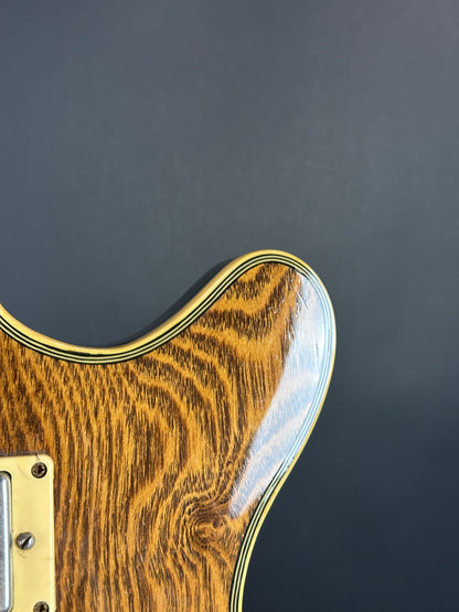 Close-up of a guitar's wooden body and gold hardware on a dark background