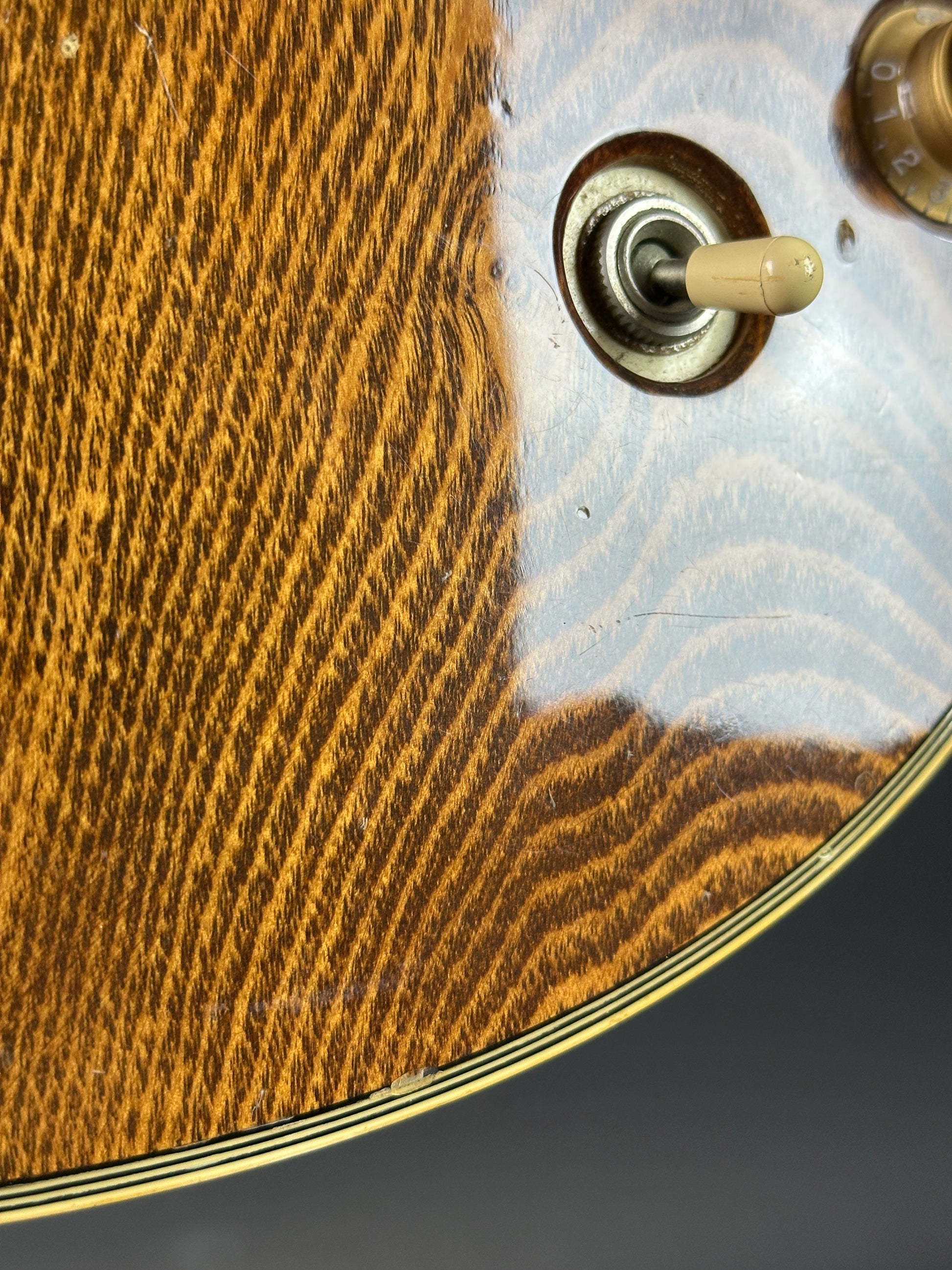 Close-up of a guitar's soundhole with a wooden finish and metal tuning peg.