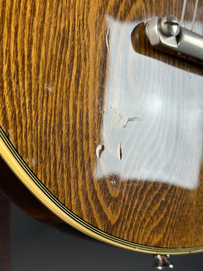 Close-up of a wooden guitar with a visible brand name on the back