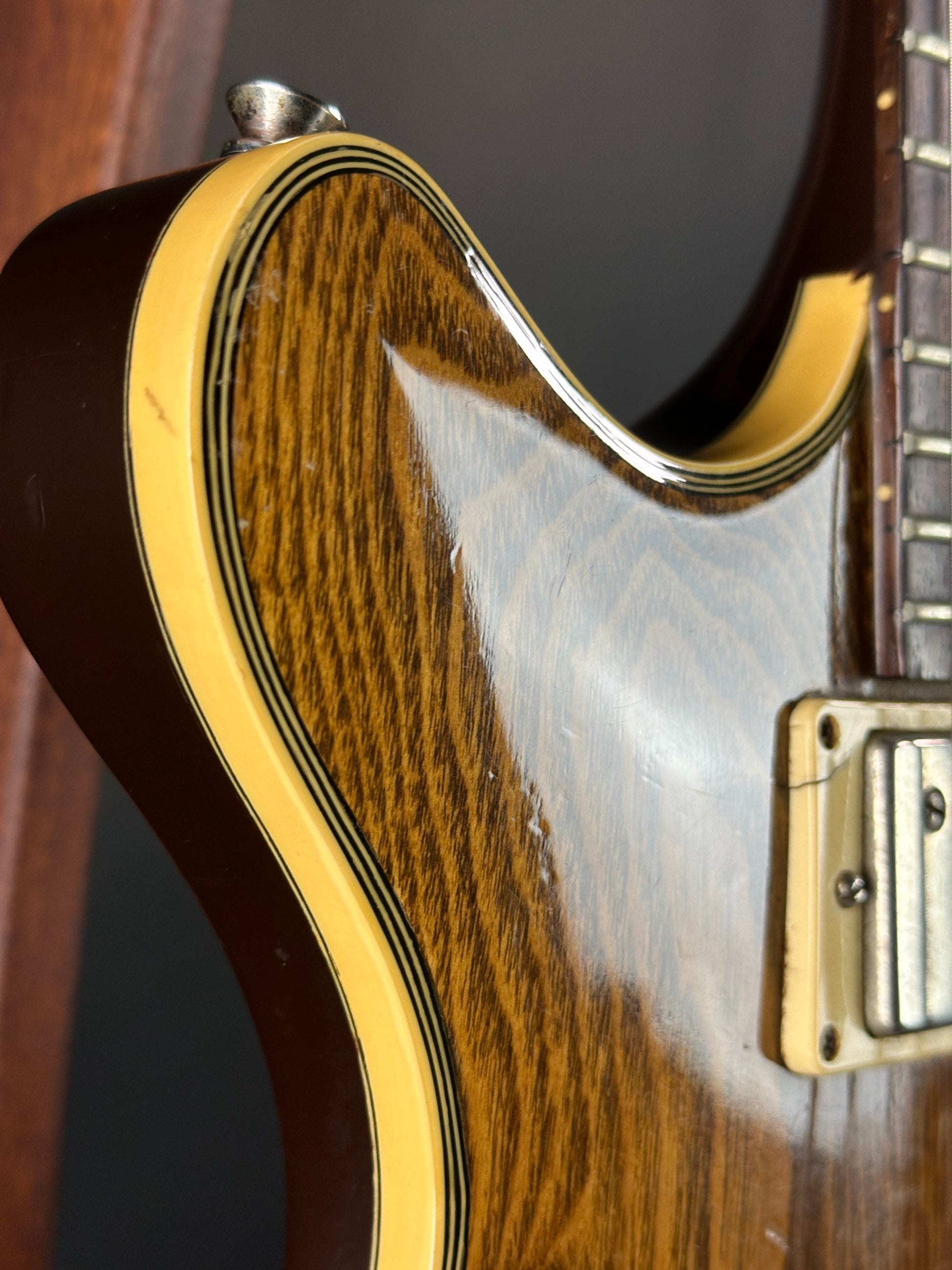 Close-up of a guitar's neck and body with a focus on the wood grain and finish.