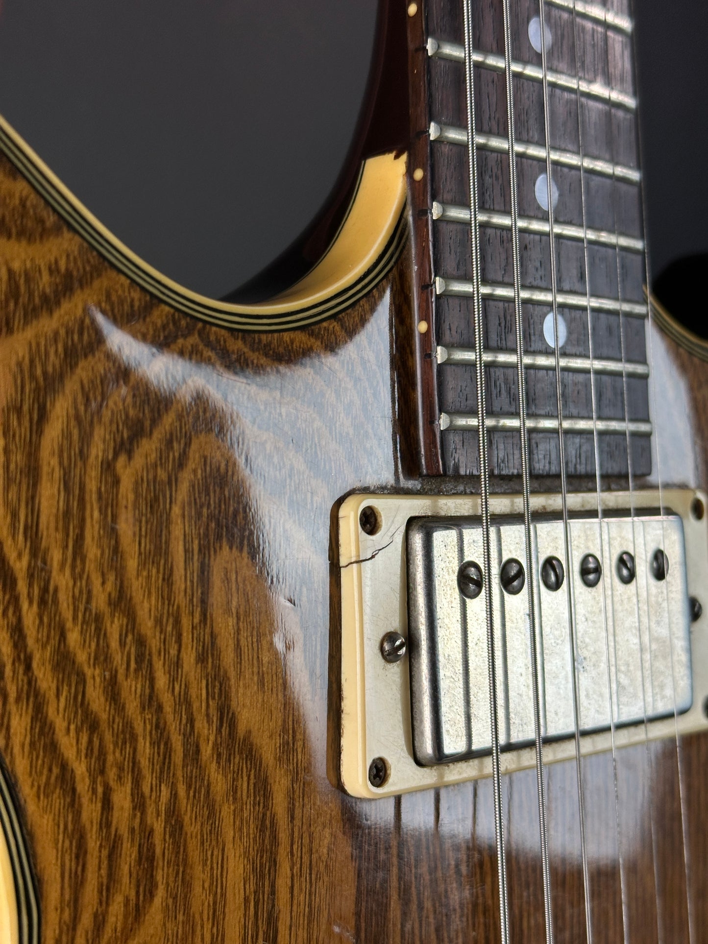 Close-up of a guitar's neck and bridge with a wooden finish